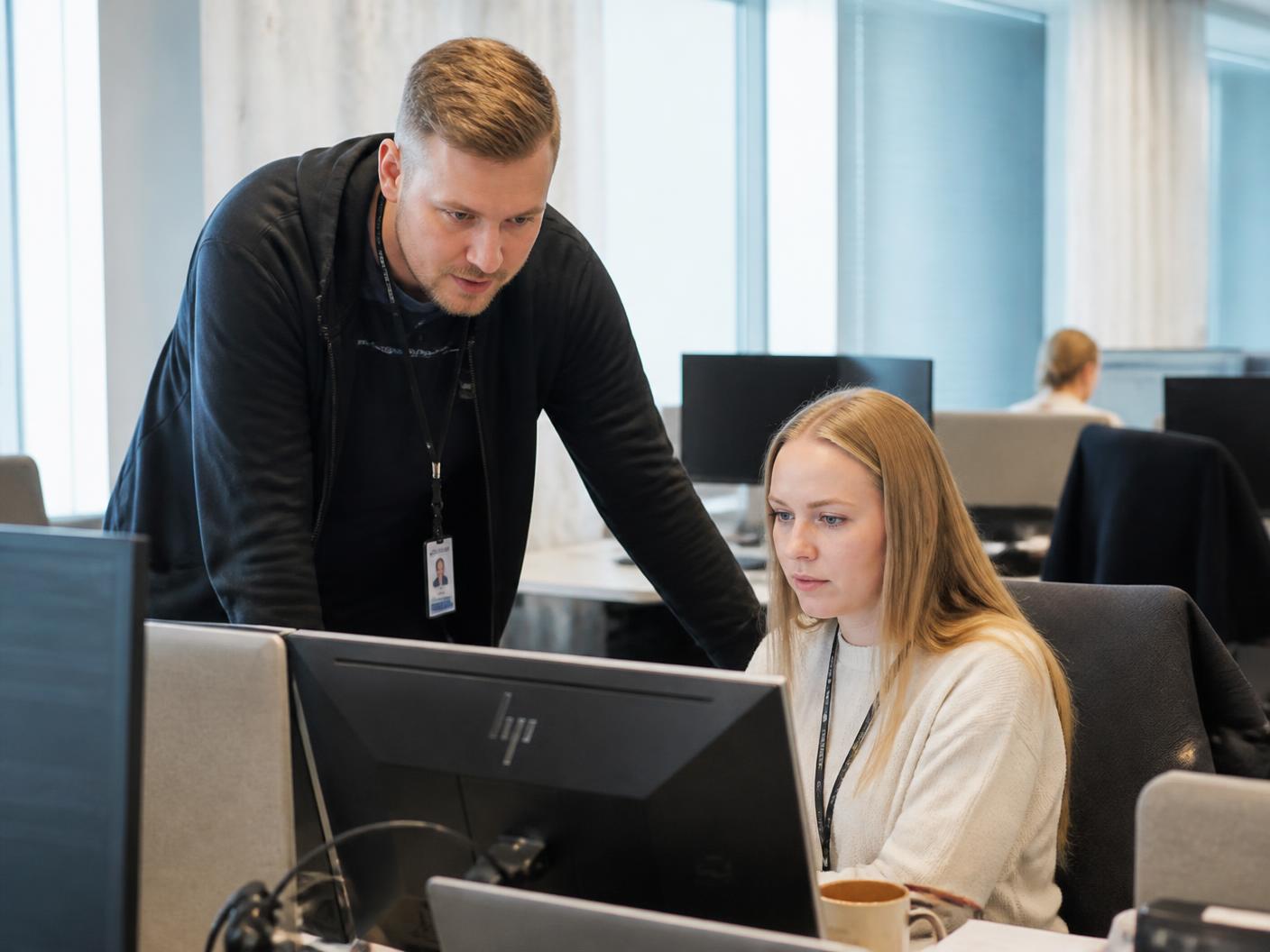 Rootsysin asiantuntija auttaa käyttäjää työaseman ääressä toimistossa